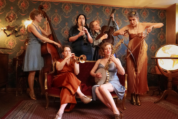 Group of women playing musical instruments in a vintage-style room.