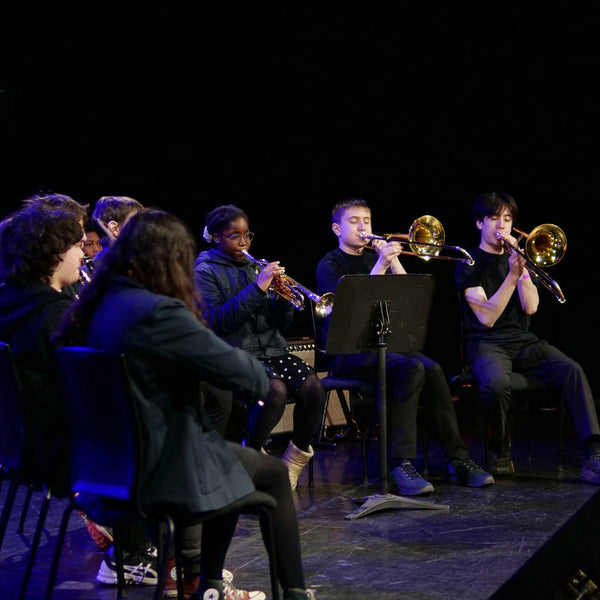 Band practice with musicians playing brass instruments and a conductor on stage.